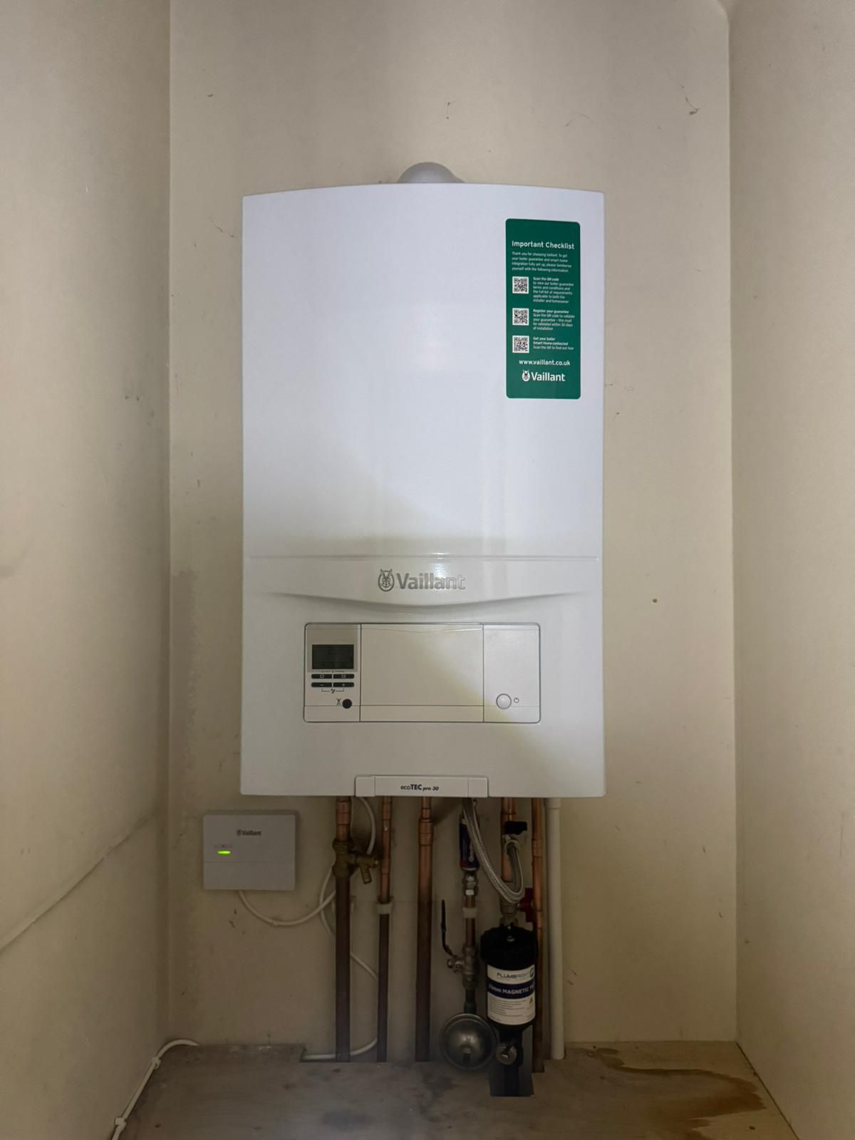 Modern wall-mounted combi boiler with neat copper pipework and brass valves in a domestic utility room